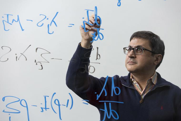 Professor Pejman Rohani works on equations on the board inside the Ecology...