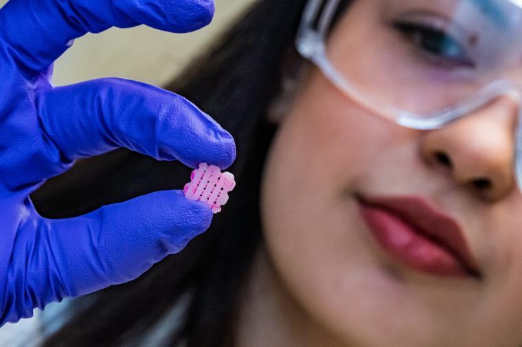 研究科学家Maryam Elizondo手持一个3D打印支架，上面刻着……